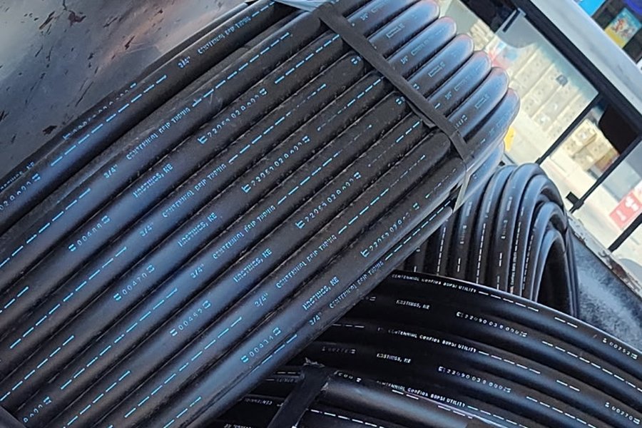 Coils of black poly irrigation pipe and drip tubing loaded in a truck bed